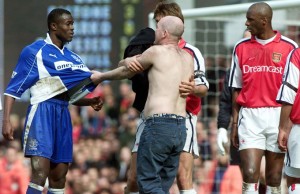 THIS PICTURE CAN ONLY BE USED WITHIN THE CONTEXT OF AN EDITORIAL FEATURE. NO WEBSITE/INTERNET USE UNLESS SITE IS REGISTERED WITH FOOTBALL ASSOCIATION PREMIER LEAGUE. Everton's Alex Nyarko (left) has his shirt pulled by a fan who ran onto the pitch at the end of the FA Carling Premiership game against Arsenal at Highbury, London.